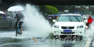 閃 潘家園橋下，汽車掀起的積水飛濺到騎自行車人的身上。本報(bào)記者 尹亞飛 攝