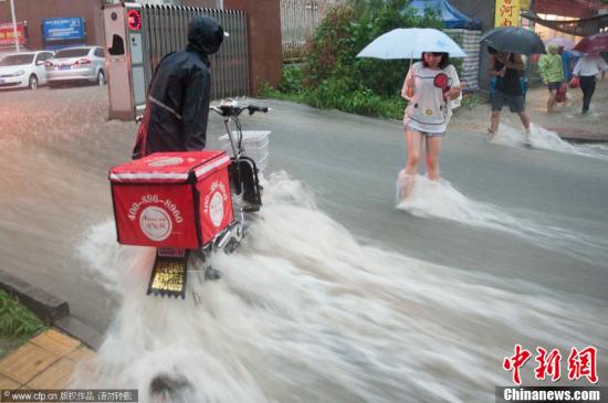 2012年7月21日，北京普降暴雨，朝陽(yáng)區(qū)北部立水橋南地區(qū)積水嚴(yán)重。一小區(qū)門口，積水沿斜坡形成巨大水流，阻礙人們通行。圖片來(lái)源：CFP視覺(jué)中國(guó)