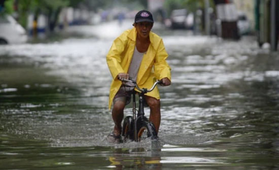 菲律賓暴雨，馬尼拉洪澇災害，一名騎自行車的男子涉水穿過被洪水淹沒的街道。